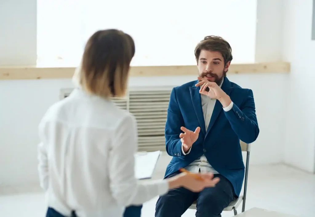 A man in individual therapy is talking to the therapist. It looks as if he is reliving some trauma and is slightly distressed.