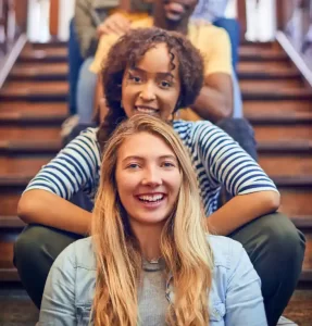 A group of happy people sat one behind the other on a staircase.